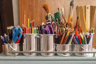 paint brushes, scissors, and rulers in buckets